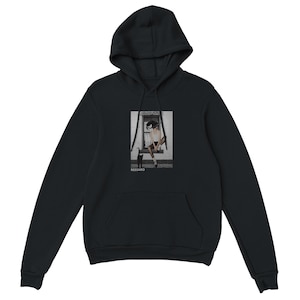 May include: Black hooded sweatshirt with a front pocket and a drawstring hood. The sweatshirt features a graphic print of a person sitting in a window with a black cat. The word "RESSARO" is printed below the graphic.