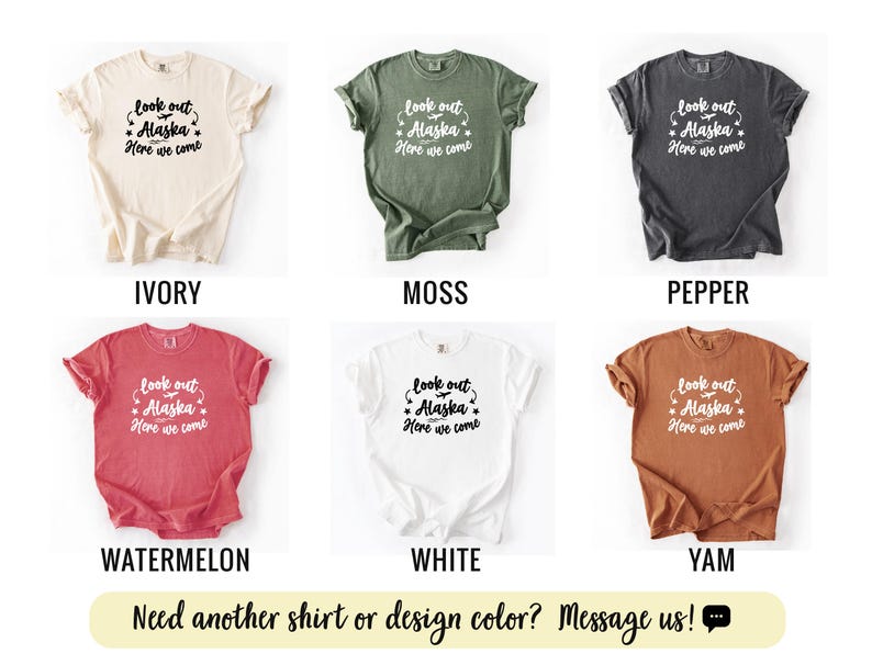 May include: A collection of six t-shirts in various colors: ivory, moss, pepper, watermelon, white, and yam. Each shirt features the text "look out Alaska, Here we come" in a decorative font. The bottom of the image has the text "Need another shirt or design color? Message us!"