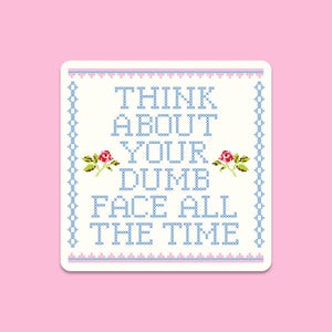Op de afbeelding: Een vierkante sticker met een kruissteekontwerp op een roze achtergrond. De sticker bevat de tekst "THINK ABOUT YOUR DUMB FACE ALL THE TIME" in blauw, met bloemaccenten.