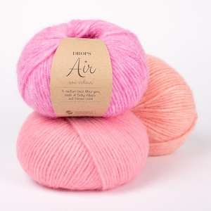 Peut inclure: Trois pelotes de fil de couleur rose et pêche. Le fil est étiqueté "DROPS Air uni colour" et est décrit comme un fil bouclé moyen épais, composé d'alpaga bébé et de laine mérinos.