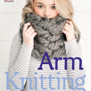 Op de afbeelding: Een vrouw draagt een grijze gebreide sjaal met een cowl-hals en een gestreepte grijze en witte trui. De tekst "Arm Knitting" staat in blauwe letters op de afbeelding. De tekst "30 naaldloze projecten voor jou en je huis" staat in zwarte letters op de afbeelding.