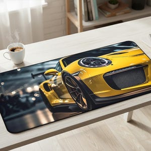 May include: A rectangular desk mat featuring a vibrant yellow sports car. The car's front is prominently displayed, showcasing its headlights, grill, and sleek design. The background is blurred, suggesting speed and motion. The mat is on a light-colored desk.