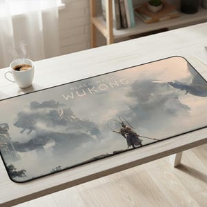 May include: Rectangular mousepad featuring a fantasy landscape with the text "BLACK MYTH WUKONG". The design includes a warrior figure and a large, imposing creature in a misty environment. The mousepad is on a white desk.