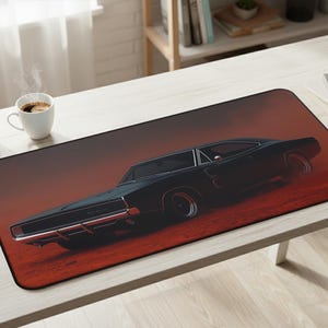 May include: Black car mousepad with a classic muscle car design. The car is set against a red and orange background, creating a dramatic effect. The mousepad is rectangular and has a black border.
