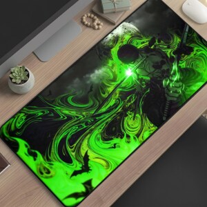 May include: A rectangular mousepad featuring a fantasy warrior design. The artwork depicts a figure with a glowing green sword amidst swirling green and black smoke, with bats in the background. The mousepad has a black border and is placed on a wooden desk.
