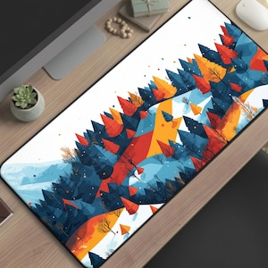 May include: A rectangular mouse pad featuring a colorful abstract landscape design. The artwork depicts stylized trees in shades of blue, orange, and red against a white background. The mouse pad is rectangular and appears to be made of a smooth material.