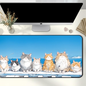 May include: A rectangular desk mat featuring a watercolor illustration of seven fluffy cats of various colors, set against a blue sky and snowy landscape. The cats are arranged in a row, with a white border.