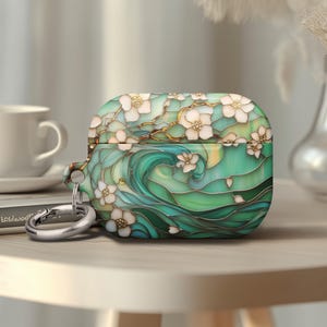 May include: A green and white Airpods case with a floral and wave design. The case has a silver metal keychain attached.