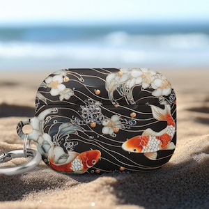May include: Black AirPod case with a koi fish design. The case features two orange and white koi fish, white flowers, and a wave pattern. A silver carabiner clip is attached to the case.