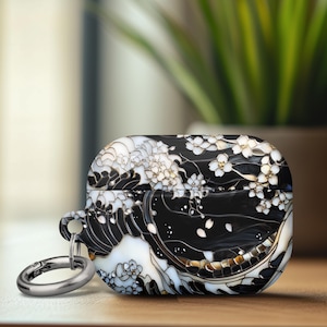 May include: A black and white Airpods case with a floral and wave design. The case has a silver metal keychain attached.