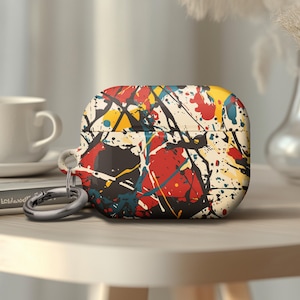 May include: A white, black, red, and blue Airpods case with a paint splatter design. The case has a silver metal carabiner attached.