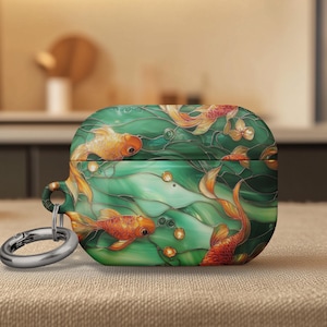 May include: A green and gold case featuring a koi fish design. The case has a silver ring attachment. The design includes orange koi fish swimming in a green pond with bubbles. The case is likely for earbuds.