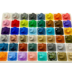 A rectangular display board containing forty small, varied colored 3D-printed swirl samples.