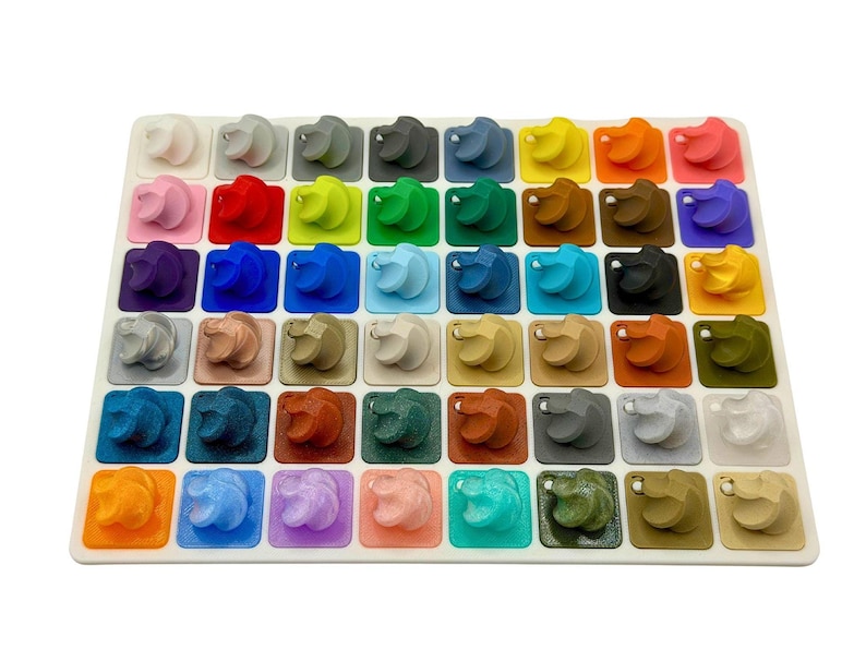 A rectangular display board containing forty small, varied colored 3D-printed swirl samples.