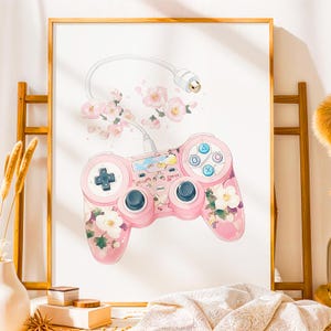 以下が含まれることがあります： ピンクの花柄のビデオゲームコントローラーと白いコード。コントローラーは青、緑、赤のボタン配置。背景は白でピンクの花が咲いている。