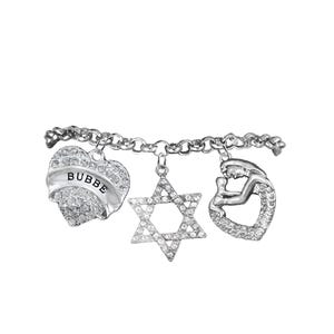 May include: A silver charm bracelet featuring three charms: a heart with the word "BUBBE", a Star of David, and a mother-and-child design. All charms are encrusted with small, sparkling crystals.