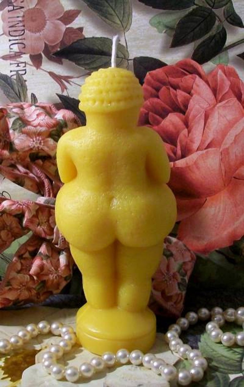 以下が含まれることがあります： 人間のシルエットの形をした黄色の蜜蝋のろうそく。ろうそくは小さな丸い台座の上に立っています。