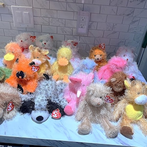 May include: A collection of 17 colorful plush toys, including a duck, a raccoon, a pig, a fox, and a giraffe. The toys are all made of soft, fuzzy fabric and have bright, cheerful colors.