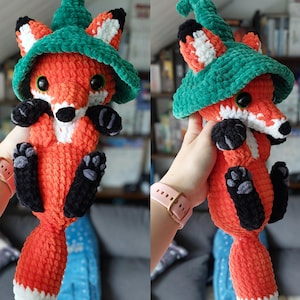Può includere: Un peluche a forma di volpe arancione fatta a mano con un cappello verde. La volpe ha zampe, orecchie e naso neri, con dettagli bianchi sul viso e sulla coda. Il peluche è realizzato in filato morbido e strutturato.