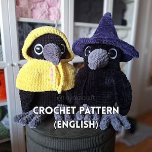 Può includere: Due bambole corvo all'uncinetto con corpi neri e becchi grigi. Un corvo indossa un mantello giallo con cappuccio e bottoni rosa, l'altro indossa un cappello a punta viola. Il testo CROCHET PATTERN (ENGLISH) è centrato sopra le bambole.