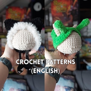 May include: Two crocheted plush toys are held in hands. One is a black and white cat-eared hat with a fluffy white face. The other is a green and white acorn-shaped toy. The text "CROCHET PATTERNS (ENGLISH)" is displayed.