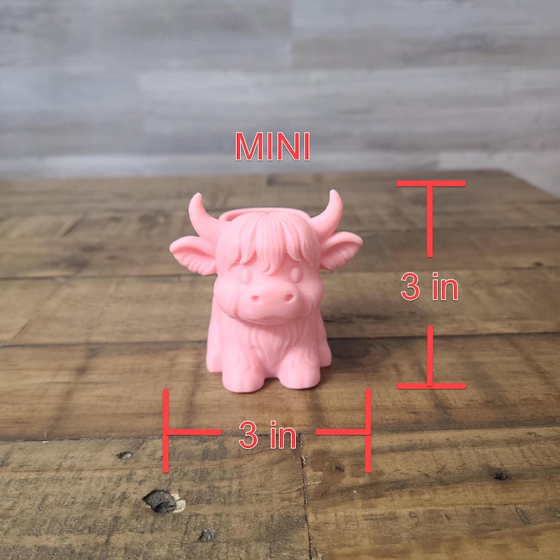 May include: A mini pink Highland cow figurine, approximately 3 inches tall and 3 inches wide. The figurine has a detailed design with horns and shaggy fur. The word "MINI" is displayed above the figurine.