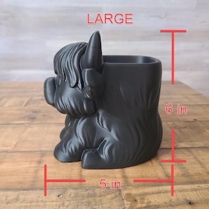 May include: Black Highland cow planter, 6 inches tall and 5 inches wide. The planter is shaped like a Highland cow with a textured surface. The word "LARGE" is printed in red at the top. Perfect for succulents or small plants.
