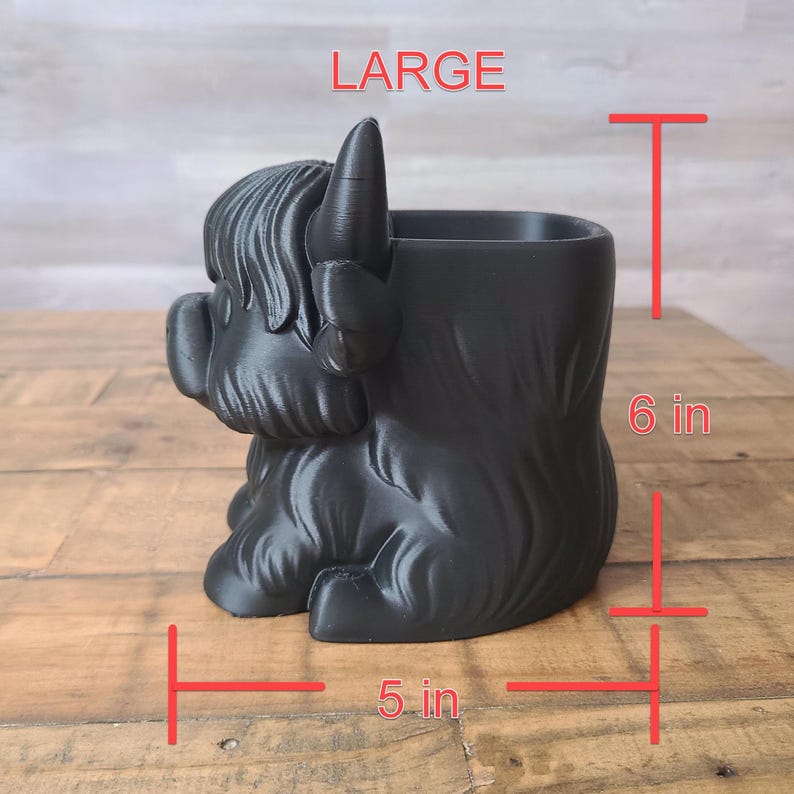 May include: Black Highland cow planter, 6 inches tall and 5 inches wide. The planter is shaped like a Highland cow with a textured surface. The word "LARGE" is printed in red at the top. Perfect for succulents or small plants.