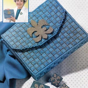 May include: A blue, handcrafted purse with a flap closure and a decorative gold-colored emblem. The purse features a grid-like pattern and is accompanied by matching square earrings. The overall design suggests a handmade craft item.