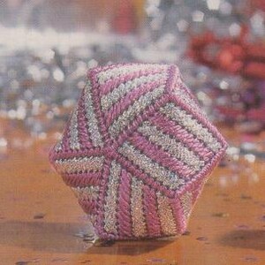 May include: A pink and silver geometric ornament with a swirling pattern. The ornament is made of fabric and has a 3D shape.