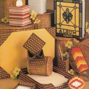 May include: A set of brown wicker baskets and containers with a brown and white plaid design. The containers are decorated with a variety of patterns, including a floral design and a stained glass window design. The set includes a tissue box holder, a pencil holder, a desk organizer, and a photo album. The album has the word "ALBUM" printed on the front.