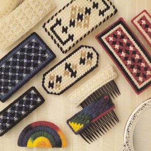 May include: Assortment of colorful plastic canvas hair clips with geometric and floral patterns. The clips are handmade and feature a variety of colors, including red, blue, black, white, and gold.