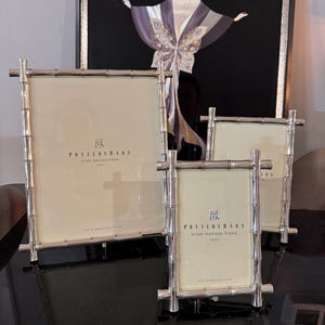 May include: A set of four silver bamboo-style picture frames of varying sizes. Each frame has a cream-colored mat and the Pottery Barn logo. The largest frame is 8 x 10 inches (20 x 25 cm).