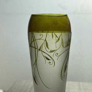 May include: A tall, clear glass vase with a frosted lower half and a translucent olive-green top. The vase is decorated with delicate green leaf and vine designs, creating an elegant and natural aesthetic.