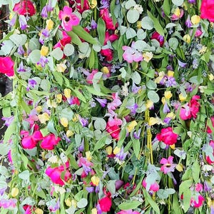 May include: A collection of artificial flower garlands with pink, yellow, and purple flowers. The garlands are made of silk and are perfect for adding a touch of color and beauty to any home.