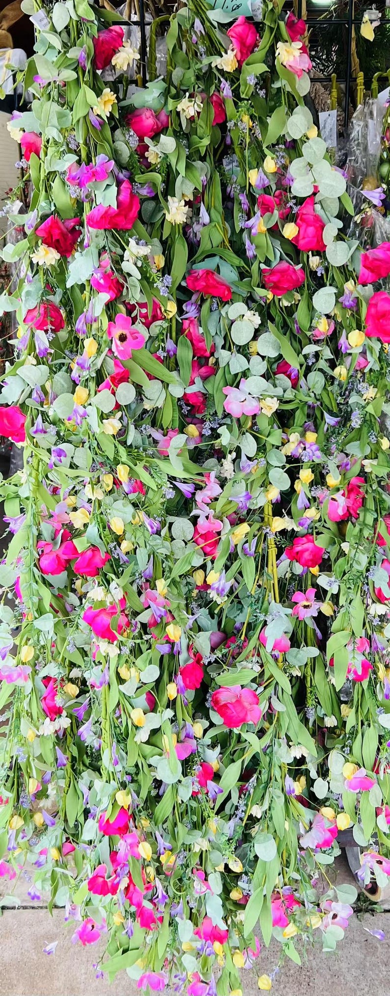 May include: A collection of artificial flower garlands with pink, yellow, and purple flowers. The garlands are made of silk and are perfect for adding a touch of color and beauty to any home.