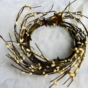 May include: A white berry wreath with rustic metal star accents. The wreath is made of natural twigs and is perfect for adding a touch of farmhouse charm to your home decor.