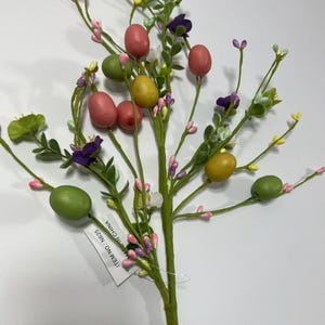 May include: A green stem with pink, purple, and white flowers and green, yellow, and pink eggs. The stem has a tag that reads "ITEM NO: NG25 MADE IN CHINA".