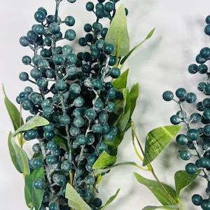 May include: A bunch of faux greenery with dark green berries and leaves. The berries have a frosted look.