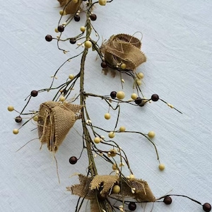 May include: A brown burlap garland with white and brown berries. The garland is made of twigs and has a rustic look.
