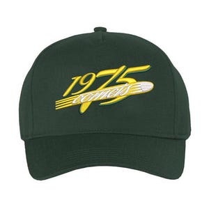 May include: A dark green baseball cap with the embroidered text "1975 comets" in yellow and white. The cap has a curved brim and a button on top. The text is stylized with a retro design.