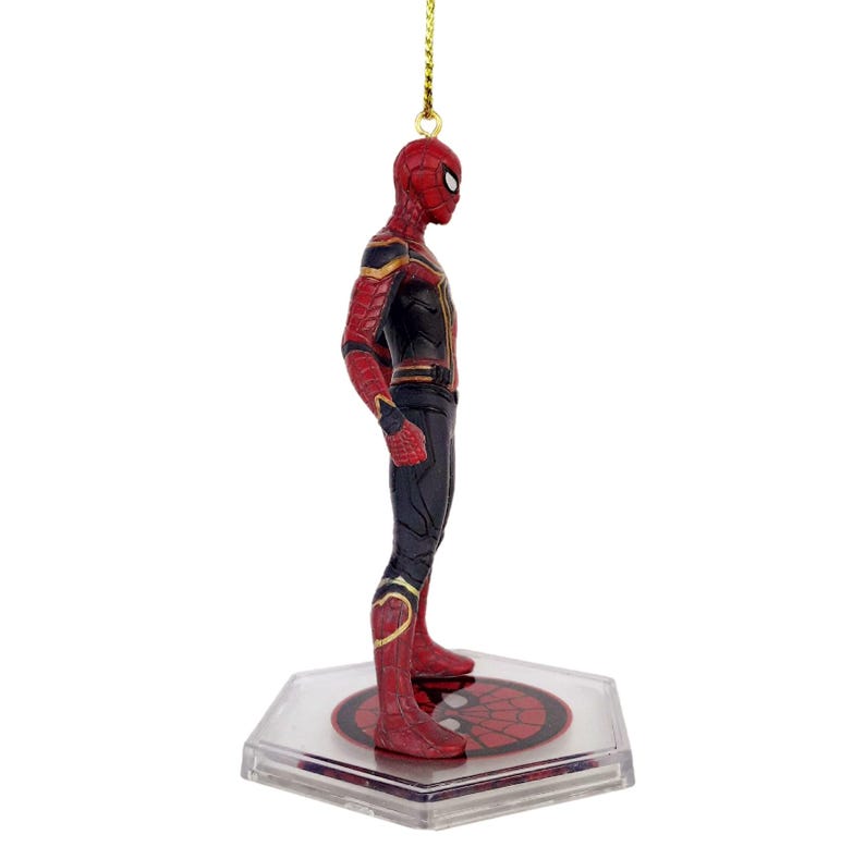 May include: A Spider-Man figurine in a red and black suit with gold accents. The figure is standing on a clear, hexagonal base with a red spiderweb design. A gold string is attached for hanging.