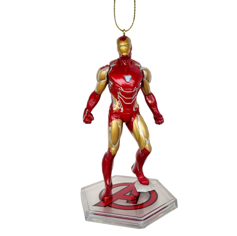 以下が含まれることがあります： アイアンマンのフィギュアオーナメント。フィギュアは赤と金で、メタリックな仕上がりです。赤色のアベンジャーズのロゴが入った透明なベースの上に立っています。吊り下げ用の金色の紐が付いています。