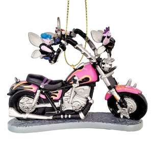 May include: A pink and black motorcycle ornament with two fairies riding on it. The motorcycle has flames painted on the side and a silver exhaust pipe. The fairies have wings and are wearing black leather jackets.