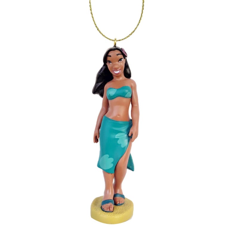 Peut inclure: Figurine d'une femme en haut de bikini et par&eacute;o turquoise, avec une cha&icirc;ne dor&eacute;e. La figurine est debout sur une base jaune, portant des sandales bleues. La femme a les cheveux noirs et une fleur dans les cheveux.