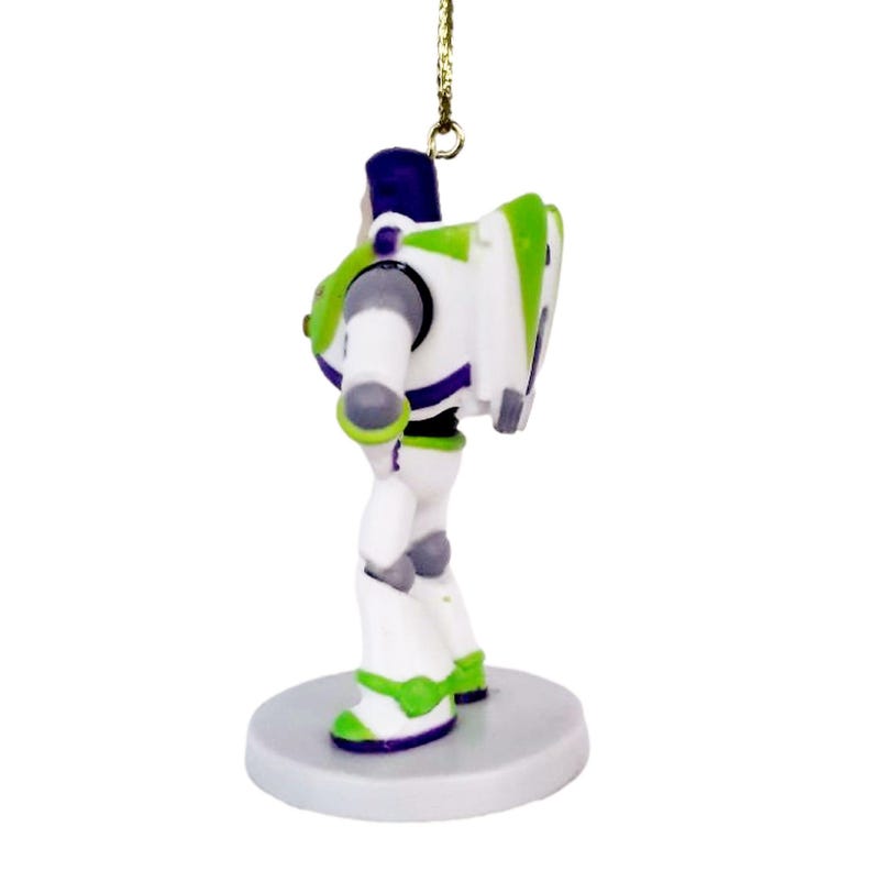 May include: A white, green, and purple plastic figurine of Buzz Lightyear from the Toy Story franchise. The figurine is standing on a white base and has a gold string attached to the top of its head.