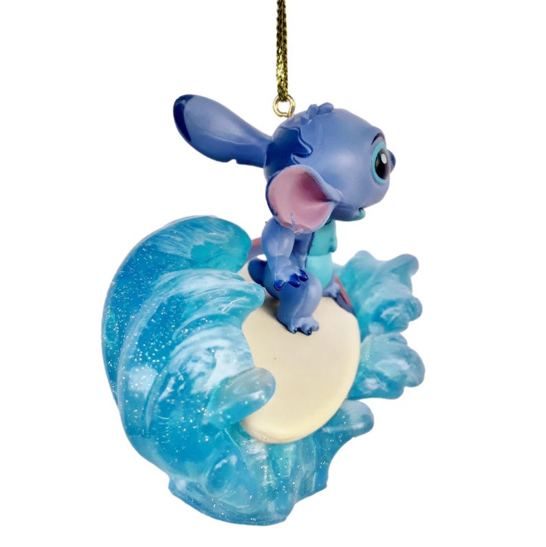 May include: A blue Stitch figurine riding a surfboard on a wave. The figurine has large ears, a pink nose, and a small blue body. The wave is a translucent blue with white accents, and the surfboard is off-white.