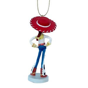 May include: A figurine of a character from the animated film Toy Story. The character is wearing a red hat, white shirt, blue jeans, and red boots. The figurine is standing on a small, round, light blue base and has a gold string for hanging.