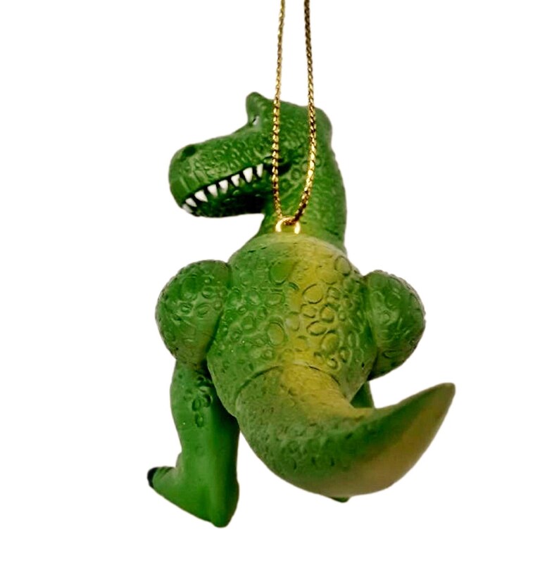 Puede incluir: Adorno de Navidad de dinosaurio de pl&aacute;stico verde con una cuerda dorada para colgar. El dinosaurio est&aacute; de pie con la cola enroscada.