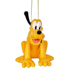 Puede incluir: Un adorno de plástico amarillo y negro de Pluto, un perro de dibujos animados de Disney. Pluto está sentado con la lengua fuera y las orejas levantadas. El adorno tiene una cuerda dorada para colgar.